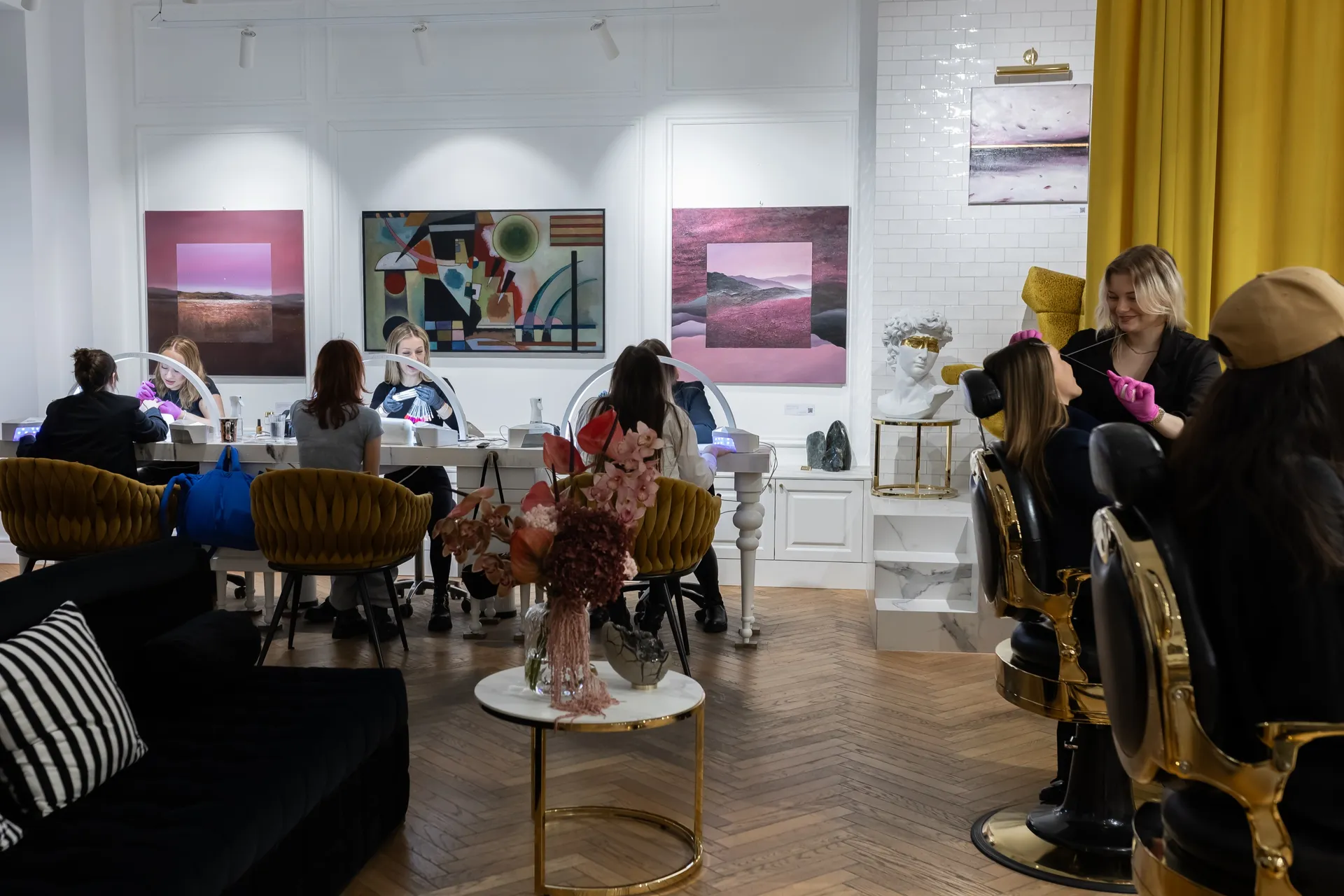 Specjalistki L'ARTE przy pracy: stylizacja brwi i manicure w sali z obrazami